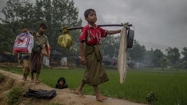 A Rohingya Muslim boy, Rahim Ullaha, right, carries his belongings as they shift to another place after their shelter was inundated with rain water at Kutupalong refugee camp, Bangladesh, Tuesday, Sept. 19, 2017.(AP)