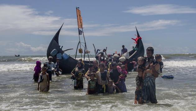 In this September 14, 2017 file photo, a Rohingya man carries two children to shore in Shah Porir Dwip, Bangladesh, after they arrived on a boat from Myanmar.(AP)