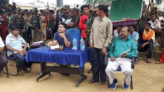 Podiyam Panda stands on the left of Sukma SP Abhishek Meena (sitting in blue T-shirt) at a public outreach programme held at Chintagufa village on August 24.(HT Photo)