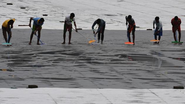 The ground staff worked hard to remove the excess water from the covers. (AFP) The ground staff worked hard to remove the excess water from the covers. (AFP)
