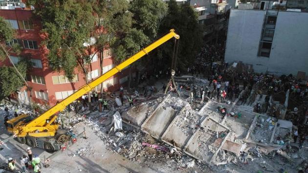 Rescuers with a crane look for survivors in a multistory building flattened by a powerful quake in Mexico City.(AFP Photo)
