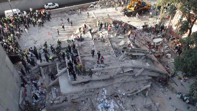 Rescuers look for survivors in a multistory building flattened by a powerful quake in Mexico City.(AFP Photo)