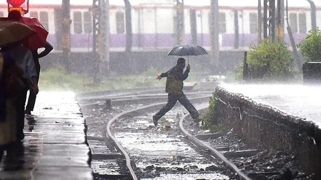 A man crosses a waterlogged railway track to catch the train at CST station. (Pratik Chorge/HT Photo)