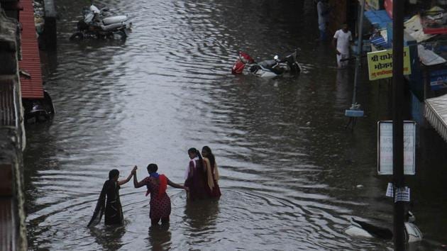Commuters walk make their way on a flooded road outside Nallasopara station. (Pramod Thakur/HT PHOTO)