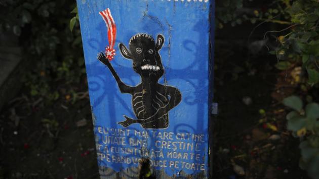 At the entrance of Romania’s Merry Cemetery, a cross bears a naive depiction of death along with a text that reads ‘Take a good look Christian, I am stronger than you, I am the ugly death, I'll carry you away one by one.’ (Vadim Ghirda / AP) At the entrance of Romania’s Merry Cemetery, a cross bears a naive depiction of death along with a text that reads ‘Take a good look Christian, I am stronger than you, I am the ugly death, I'll carry you away one by one.’ (Vadim Ghirda / AP)