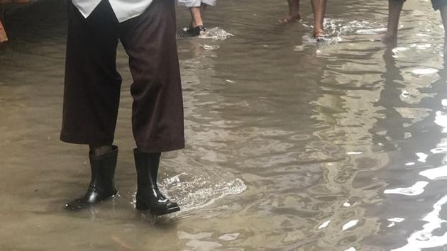 Residents of Amar Deep Society, Hadapsar wading through stagnated drainage water in their parking area.(HT PHOTO)
