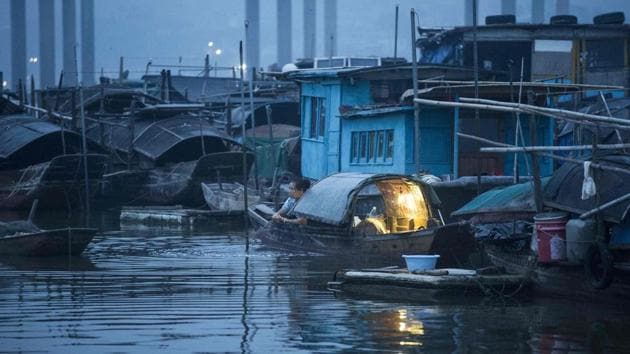 Boats are parked haphazardly along the shore, their decks packed with fishing equipment, blankets and sometimes people sleeping. Men and women in straw hats balance rods holding nets of carp on either end. (Fred Dufour / AFP)