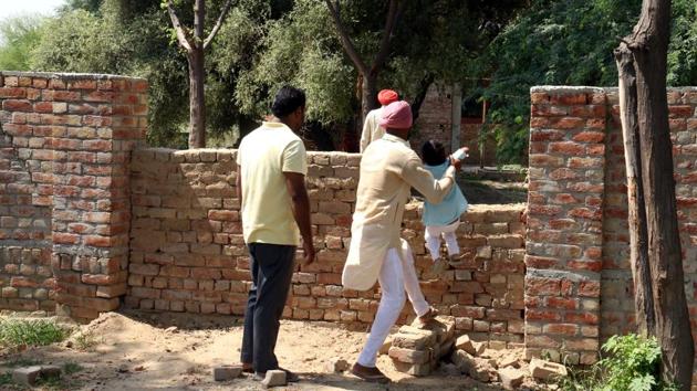 People from Scheduled Caste (Dalit) community crossing a wall to enter the separate cremation ground for them in Kot Guru village as no thoroughfare has been left for them except a detour through a dumping ground.(Sanjeev Kumar/HT)