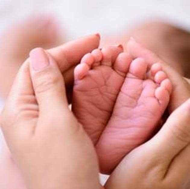 Mother holding tiny foot of newborn baby(Getty Images/iStockphoto)