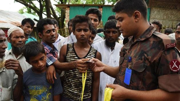 Rohingya refugee receive new ID card from a soldier at the entrance of the Bangladeshi government registration office at the refugee camp of Kutupalong near in Ukhia on September 22.(AFP Photo)