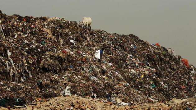 A portion of the 45 metre high garbage dump in east Delhi’s Ghazipur had collapsed due to heavy rains, killing two people and pushing a car and three two- wheelers off the road, into a canal.(Ajay Aggarwal/HT Photo)