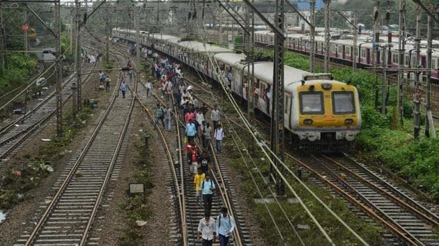 Commuters walk on railway tracks as train services slowly resume in Mumbai on August 30.(AFP Photo)