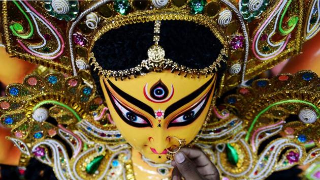 An Indian artisan puts a nose ring as he gives finishing touches on a clay idol of the Hindu Goddess Durga at his workshop in Chennai on September 20, 2017. Durga Puja, the annual Hindu festival that involves worship of the goddess Durga who symbolizes power and the triumph of good over evil in hindu mythology, culminates in the immersion of idols in water bodies. (Arun Sankar / AFP) An Indian artisan puts a nose ring as he gives finishing touches on a clay idol of the Hindu Goddess Durga at his workshop in Chennai on September 20, 2017. Durga Puja, the annual Hindu festival that involves worship of the goddess Durga who symbolizes power and the triumph of good over evil in hindu mythology, culminates in the immersion of idols in water bodies. (Arun Sankar / AFP)
