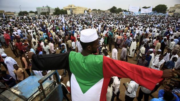 A man dressed in a garb coloured as the Sudanese national flag stands in a crowd gathered to receive President Omar al-Bashir (unseen) during his tour in Nyala, the capital of South Darfur province, on September 21, 2017. (Ashraf Shazly / AFP) A man dressed in a garb coloured as the Sudanese national flag stands in a crowd gathered to receive President Omar al-Bashir (unseen) during his tour in Nyala, the capital of South Darfur province, on September 21, 2017. (Ashraf Shazly / AFP)