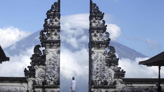 Balinese man watches Mount Agung volcano almost covered with clouds as he stands at a temple in Karangasem, Bali, Indonesia, Tuesday, September 26.(AP)