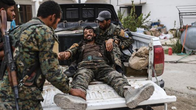 A heavily wounded member of the Syrian Democratic Forces smiles as he arrives at a medical centre on the eastern frontline of Raqqa on September 24, 2017. The sporadic sound of gun and mortar fire could be heard, but among the SDF spirits were running high. SDF commander Rojda Felat said the remaining IS fighters in the city ‘no longer have the ability to launch attacks or dispatch car bombs.’ (Bulent Kilic / AFP) 
