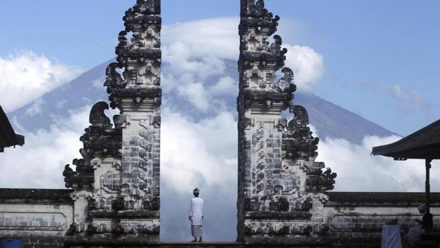 A Balinese man looks on from a temple in Karangasem as Mount Agung volcano is shrouded in clouds. The National Disaster Mitigation Agency’s command post in Bali said the number of evacuees has swelled to about 134,200 by Thursday evening fearing it will soon erupt. This is more than double the estimated population within the immediate danger zone, as people farther from the mountain join those fleeing. (Firdia Lisnawati / AP) A Balinese man looks on from a temple in Karangasem as Mount Agung volcano is shrouded in clouds. The National Disaster Mitigation Agency’s command post in Bali said the number of evacuees has swelled to about 134,200 by Thursday evening fearing it will soon erupt. This is more than double the estimated population within the immediate danger zone, as people farther from the mountain join those fleeing. (Firdia Lisnawati / AP)