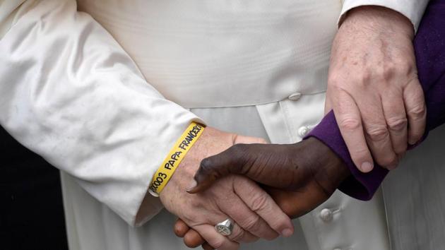 Pope Francis wears a yellow plastic ID bracelet as he shakes hand with a man during a visit to a migrant's reception centre in Bologna, Italy, on Sunday. (Reuters)