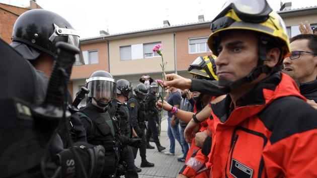 A person gives a carnation to Guardia Civil officers as firemen hold the people in front of Spanish Guardia Civil officers outside a polling station in San Julia de Ramis, on October 1, 2017, on the day of a referendum on independence for Catalonia banned by Madrid. (AFP Photo) A person gives a carnation to Guardia Civil officers as firemen hold the people in front of Spanish Guardia Civil officers outside a polling station in San Julia de Ramis, on October 1, 2017, on the day of a referendum on independence for Catalonia banned by Madrid. (AFP Photo)