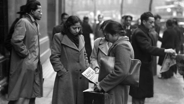 Young women seen reading a newspaper among members of London’s Indian and Pakistani population outside India House, central London, after hearing of the assassination of the Indian statesman and advocate of non-violence, Mahatma Gandhi in 1948. ( Reg Speller / Fox Photos / Getty Images)