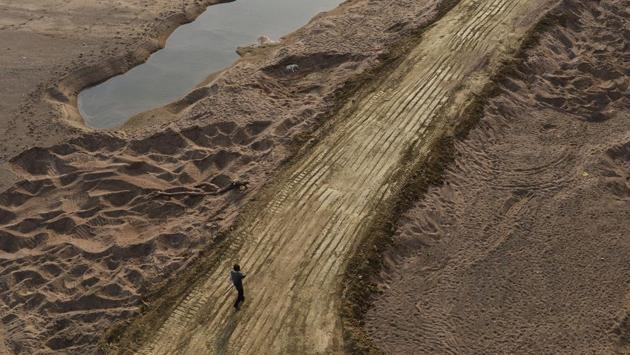 A man walks over truck tire tracks on Ken’s rich river bed. Plagued by illegal sand mining, locals allege that the involvement of the local authorities has only destroyed the ecology. (Vipin Kumar / HT PHOTO)