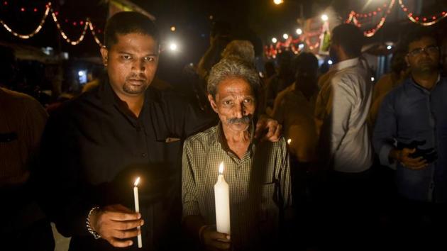 The father (right) of Mayuresh Haldankar, one of the victims of last Friday’s Elphinstone Road stampede, participates in a candle light vigil at the station on Monday.(Pratik Chorge/HT photo)