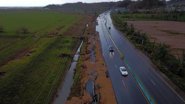 Cars drive on a highway next to downed power line poles by Hurricane Maria in Vega Alta, Puerto Rico. While the region reels in darkness, the road to rebuilding and restoring power completely across the area is expected to take atleast a month despite the financial aid from Washington. (Ricardo Arduengo / AFP)