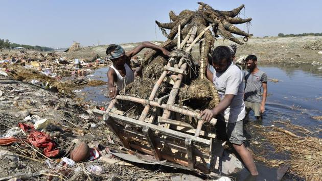 Workers from flood control department remove idols from the riverbed. Child scavengers, treasure hunters and MCD’s clean-up teams throng Delhi’s Yamuna Ghats during the immersion period. Some look for remains of idols for resale and reuse, others hunt for jewellery and coins in the debris. (Sanchit Khanna / HT PHOTO)