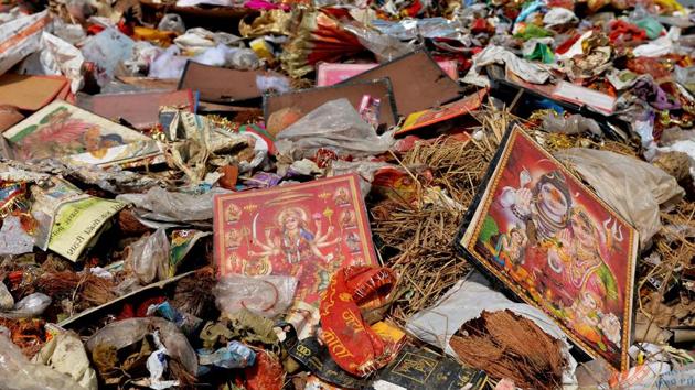 With nearly 200 Durga Puja pandals immersing idols near Delhi-NCR, the river water was clogged with plastic bags, flower petals and pooja material, besides metal structures. (Money Sharma / AFP)