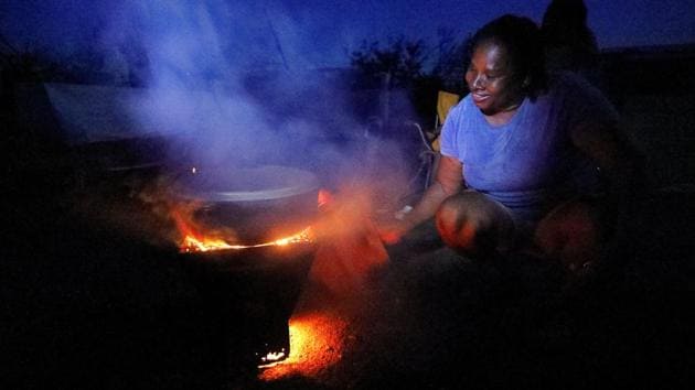Sharmaine Williams Stapleton fans a wood stove during an informal street gathering in the darkened neighbourhood of Whim Estate in the hard-hit Frederiksted area of St. Croix, U.S. Virgin Islands. The street gathering of a few families to eat and relax ‘is the best way to deal with what's happened,’she said. (Jonathan Drake / REUTERS)