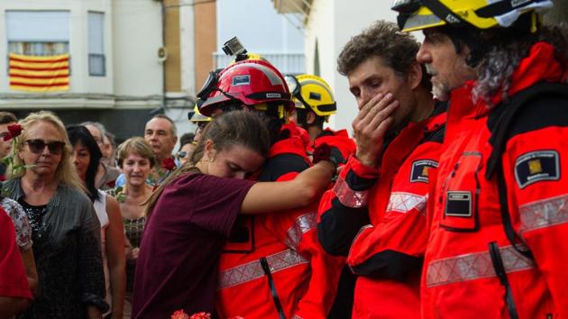 A woman hugs a fireman as others queue to lay flowers on ballot boxes used during the Catalan independence referendum in Pineda de Mar. (Lola Bou / AFP) A woman hugs a fireman as others queue to lay flowers on ballot boxes used during the Catalan independence referendum in Pineda de Mar. (Lola Bou / AFP)
