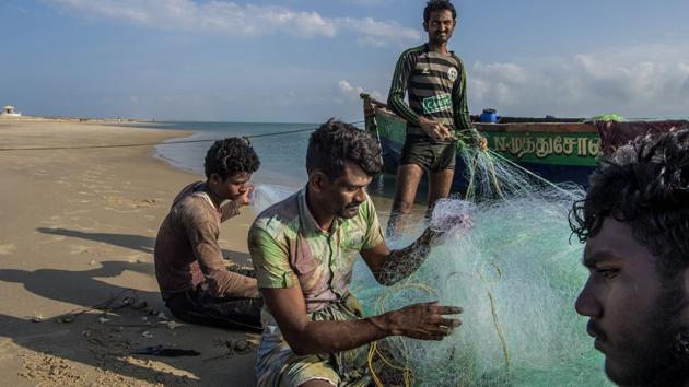 Fishermen at the Dhanushkodi beach, on Pamban Island. A group of sinewy fishermen ripping shells from a net said they had no idea what was submerged in their fishing grounds. (Atul Loke / NYT)