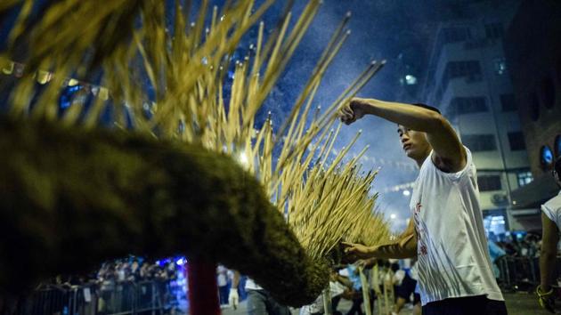 A participant adds incense sticks to the trunk of a ‘fire dragon’ as he takes part in the annual Tai Hang fire dragon event, one of the highlights of the city's Mid-Autumn festival, in Hong Kong. Throngs of festival-goers gathere in a historic neighbourhood of Hong Kong to watch a fire dragon lit with incense sticks danced through the streets in a century-old ritual. (Anthony Wallace / AFP)