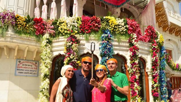 Foreign tourists taking a selfie in front of the beautifully decorated Akal Takht in Golden Temple on the birth anniversary of Guru Ram Das, in Amritsar on Friday. (Sameer Sehga/HT)