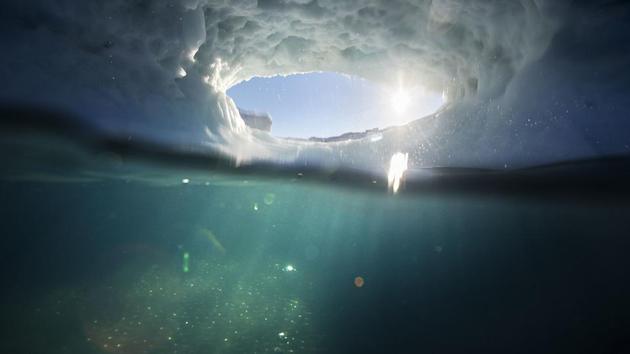 The submerged section of an iceberg is illuminated in the Nuup Kangerlua fjord near Nuuk in Greenland. A study, published in the Geophysical Research Letters, pulls together a body of evidence that measures the depth and contours of the ocean floor both beneath liquid water in Greenland’s fjords. (David Goldman / AP)