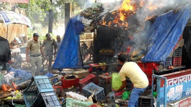 A man tries to douse fire as policemen look on after right wing activists torched a vegetable shop in Rishikesh. (HT PHOTO)