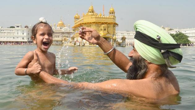 A devotee and his child take a dip in the holy sarovar (water tank). Guru Ram Das was fourth of the ten Sikh gurus. (Sameer Sehgal/HT)