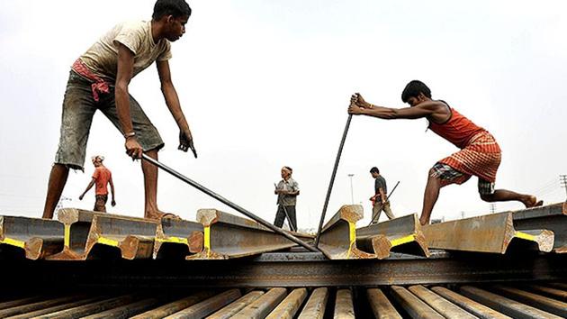 Labourers use iron bars to stack railway tracks at a railway station in Agartala.(AFP File Photo)