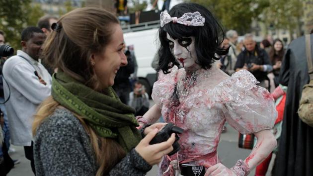A participant (R) poses for onlookers as she attends the ‘Zombie Walk’ in Paris. (AFP)