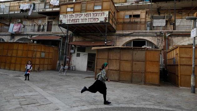 Children are seen playing at the plaza in front of their huts in Jerusalem. The Sukkah is a walled structure covered with plant material intended to evoke nostalgia of the type of dwelling in which the Israelites stayed during their 40 years of travel in the desert. (Menahem Kahana / AFP)