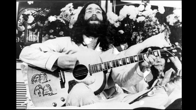 Towards the end of 1968, Lennon’s focus had moved beyond The Beatles. He started recording with Yoko Ono and their public appearances of protest became photo opportunities for the media. Here seen singing a song in bed with Ono next to him, in a hotel bed in Canada on 1st March 1969. (Keystone Features / Getty Images)
