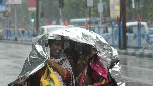 A family tries to huddle under a plastic sheet while crossing the street in busy Sealdah area on Monday afternoon.(Samir Jana) A family tries to huddle under a plastic sheet while crossing the street in busy Sealdah area on Monday afternoon.(Samir Jana)