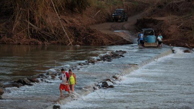 Local residents cross a river using a cable in lieu of the town’s destroyed bridge in San Lorenzo. (Alvin Baez / REUTERS)
