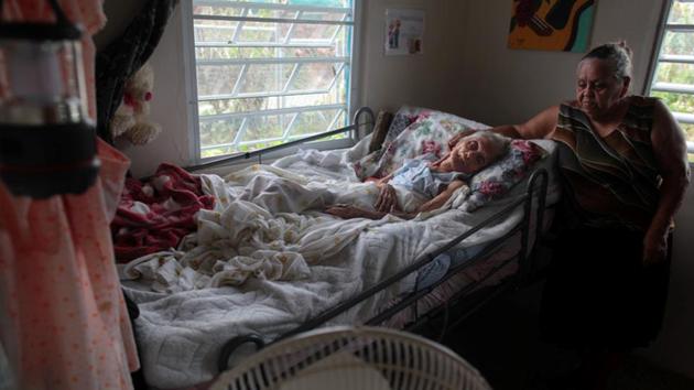 Carmen Rodrigues stands by her bedridden mother, Rosa Maria Torres, 95. ‘If they don’t move her out of here, she’s going to die,’ Carmen Santos, Torres’ granddaughter, said. Before the storm, a hospital was only a 15-minute drive away in the town of Morovis. Now, the only way out is wading across a river knee-deep as floodwaters have receded, or detouring by car on the mountain road. Santos does not think her grandmother would survive either option. (Alvin Baez / REUTERS)