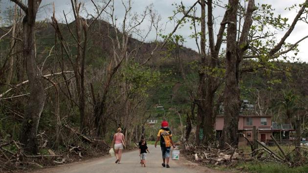 Residents walk along a devastated landscape after Hurricane Maria ravaged San Lorenzo. With schools closed until at least January and their main link to the world broken, many village residents are considering fleeing to the mainland United States. (Alvin Baez / REUTERS)