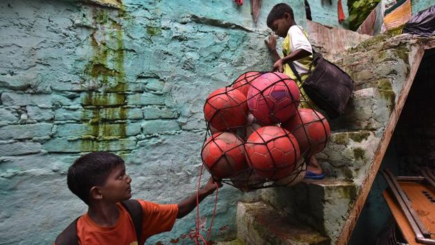 Jishan (L) helps Rohit at with a pack of footballs for training at the camp in Vikaspuri, New Delhi. At Sylvester Peter’s academy, children are trained early in the morning and football is a way of not just releasing their energy but also reforming their way of living. (RAJ K RAJ / HT PHOTO)