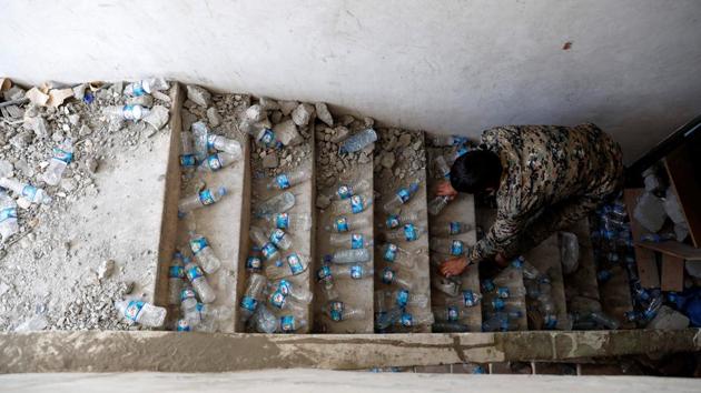 A fighter of Syrian Democratic Forces places empty plastic bottles on stairs of a building at their positions, at the frontline in Raqqa to squeak when stepped on and alert them to intruders. SDF fighters are well prepared in case the cornered IS militants attempt a breach. The front porch steps have been demolished, leaving a drop to the basement that can be crossed only by climbing a makeshift ladder, which can be pulled up. (Erik De Castro / REUTERS) A fighter of Syrian Democratic Forces places empty plastic bottles on stairs of a building at their positions, at the frontline in Raqqa to squeak when stepped on and alert them to intruders. SDF fighters are well prepared in case the cornered IS militants attempt a breach. The front porch steps have been demolished, leaving a drop to the basement that can be crossed only by climbing a makeshift ladder, which can be pulled up. (Erik De Castro / REUTERS)
