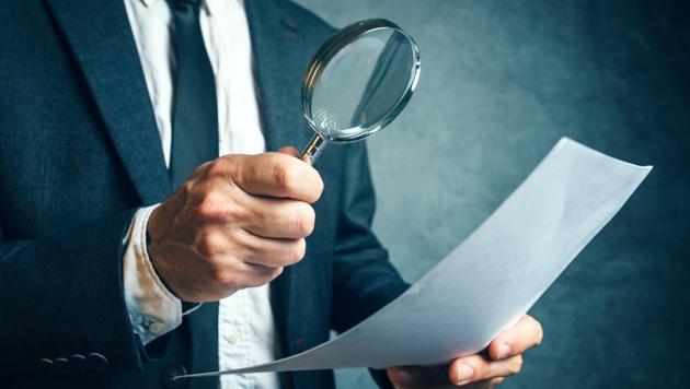 A tax inspector investigating financial documents through magnifying glass, forensic accounting or financial forensics, inspecting offshore company financial papers, documents and reports. (Getty Images/iStockphoto) A tax inspector investigating financial documents through magnifying glass, forensic accounting or financial forensics, inspecting offshore company financial papers, documents and reports. (Getty Images/iStockphoto)