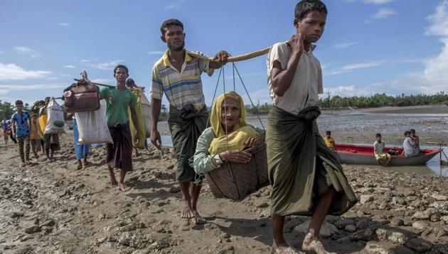 Rohingya Muslims, who crossed over from Myanmar into Bangladesh, carry an elderly woman in a basket and walk towards a refugee camp in Shah Porir Dwip, Bangladesh, in September.(AP) Rohingya Muslims, who crossed over from Myanmar into Bangladesh, carry an elderly woman in a basket and walk towards a refugee camp in Shah Porir Dwip, Bangladesh, in September.(AP)