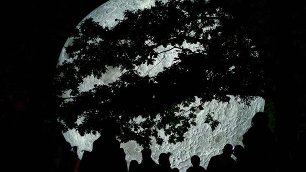 People watch a light object called "The Museum of the Moon" created by British artist Luke Jerram and displayed at the Medical Garden in Bratislava on October 7, 2017, during the White Night festival. (Joe Klamar / AFP) People watch a light object called "The Museum of the Moon" created by British artist Luke Jerram and displayed at the Medical Garden in Bratislava on October 7, 2017, during the White Night festival. (Joe Klamar / AFP)